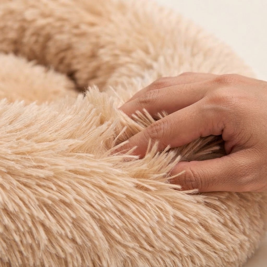 Main s'enfonçant dans la peluche longue et douce du coussin donut abricot