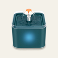Fontaine à eau pour chat coloris bleu pétrole : réservoir carré bleu-vert, rebord transparent et fleur blanche à cœur orange d'où l'eau retombe en cascade